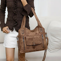 Sac à main vintage marron avec bandoulière, poche avant à rabat et deux zips latéraux.
