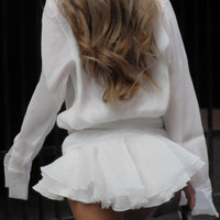 Robe courte plissée blanche : ceinture nouée, jupe à volants et manches longues amples