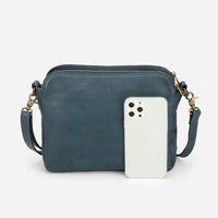 Sac à main en cuir bleu nuit, bandoulière, poche avant zippée et étui téléphone.