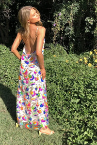 Robe fleurie fendue à bretelles, longue jupe fendue, motifs colorés sur fond clair.