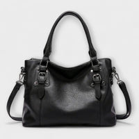 Sac à bandoulière en cuir noir, double anse et bandoulière avec anneaux métalliques.