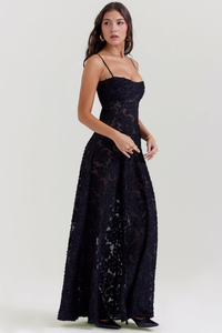 Robe longue noire à bretelles fines, dentelle florale, jupe évasée et ourlet légèrement échancré.