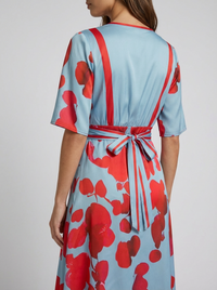 Robe longue bleu clair à fleurs rouges, dos en V et ceinture nouée à ruban