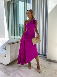 Robe mi-longue une épaule fuchsia plissée, fleur décorative sur l’épaule, clutch beige.