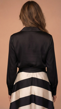 Robe noire boutonnée au dos, jupe rayée blanc et noir, nœud à la taille.