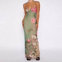 Robe longue verte fleurie, bretelles fines, décolleté en V, motifs roses et beiges au sol.