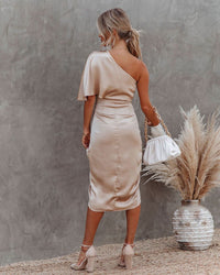 Robe midi satin beige avec une épaule, fente avant, dos en décolleté et drapé latéral.