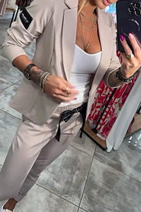 Ensemble veste et pantalon beige clair avec top blanc et détails boutonnés.