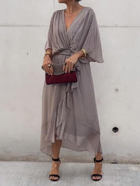 Robe midi grise à col en V, manches évasées, ceinture nouée à la taille, tombé fluide.