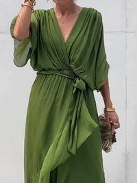 Robe midi vert foncé à col en V, manches trois-quarts bouffantes, ceinture nouée visible.