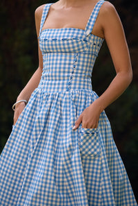 Robe midi sans manches bleu ciel à carreaux, corsage boutonné et poches latérales.