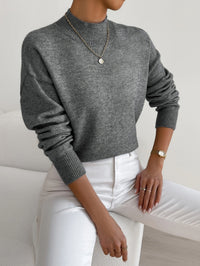 Pull minimaliste gris chiné en maille, encolure ronde, manches longues côtelées.