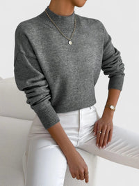 Pull à col roulé gris foncé en maille côtelée, manches longues, coupe ample.