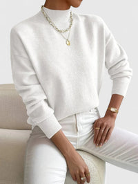 Pull à col roulé blanc en maille côtelée, manches longues, style ample.