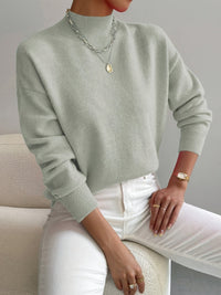 Pull minimaliste vert clair en maille, encolure ronde, manches longues côtelées.