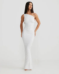 Robe longue blanche moulante, bretelles fines, décolleté asymétrique et fronces discrètes.