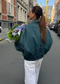 Veste en cuir oversize bleue/vert foncé portée de dos, coutures contrastées et zips.
