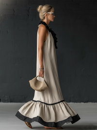 Robe longue sans manches beige, volants noirs sur l’encolure et grand volant en bas