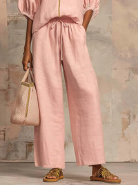 Pantalon ample rose pâle à taille froncée, jambes larges.