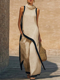 Robe longue sans manches en coton-lin beige, encolure drapée et liseré noir contrastant.