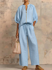 Ensemble chemise et pantalon ample bleu clair, fermeture zippée, manches bouffantes.