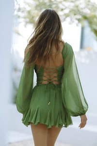 Mini-robe courte verte dos nu à laçage croisé, manches bouffantes et jupe froncée.