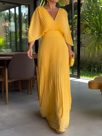 Robe longue jaune à col en V, manches chauve-souris, plis verticaux et taille cintrée.