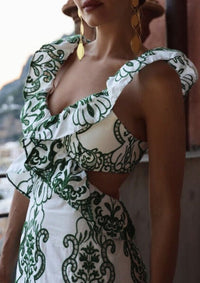 Robe longue imprimée vert et blanc, encolure carrée à volants et bretelles.