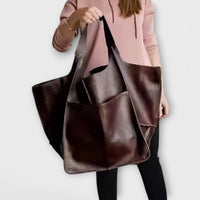Sac de voyage surdimensionné en cuir marron foncé, porté avec grande ouverture et poches