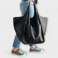 Sac de voyage surdimensionné en cuir noir, porté sur l’épaule avec grandes anses