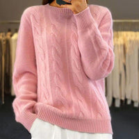 Pull en maille rose pâle, col rond, manches longues torsadées, poignets côtelés.