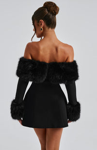 Robe courte noire vue dos, épaules dénudées avec fausse fourrure et poignets duveteux.