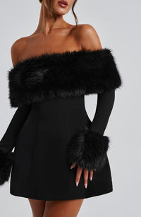 Robe courte noire à épaules dénudées, fausse fourrure épaisse sur le buste et manches.