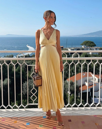 Robe longue plissée jaune à bretelles fines et décolleté en V, port de face